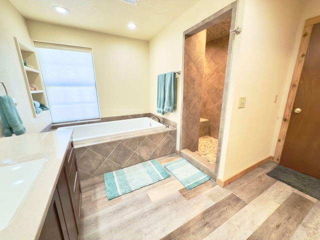 full bathroom with recessed lighting, a sink, wood finished floors, tiled shower, and a bath