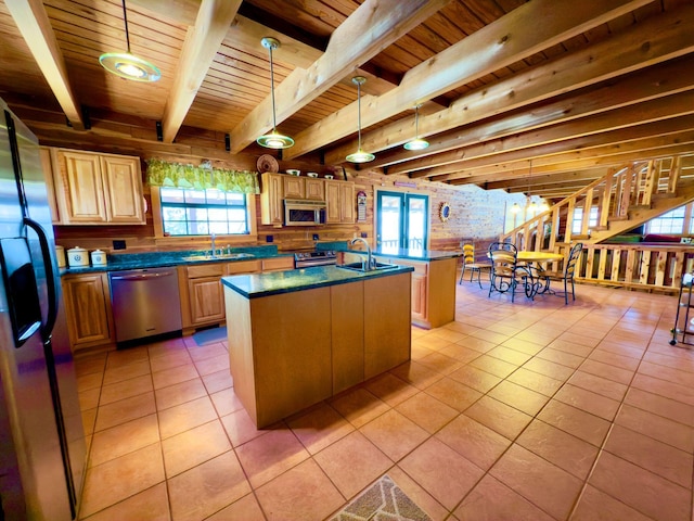 kitchen with appliances with stainless steel finishes, dark countertops, a kitchen island, and pendant lighting