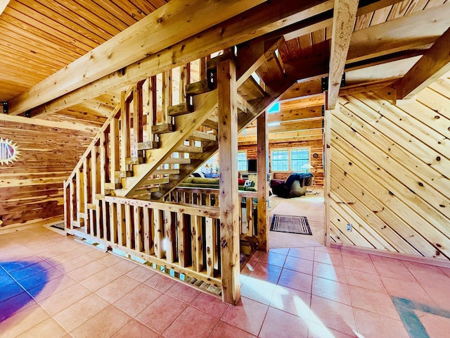 stairs featuring tile patterned flooring, wooden ceiling, wooden walls, and lofted ceiling with beams