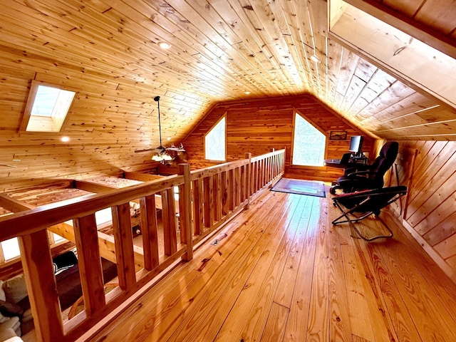 bonus room featuring lofted ceiling with skylight, light wood-type flooring, wooden ceiling, and wood walls