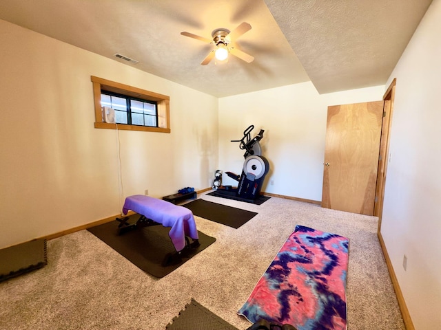 exercise area featuring visible vents, a ceiling fan, carpet flooring, a textured ceiling, and baseboards