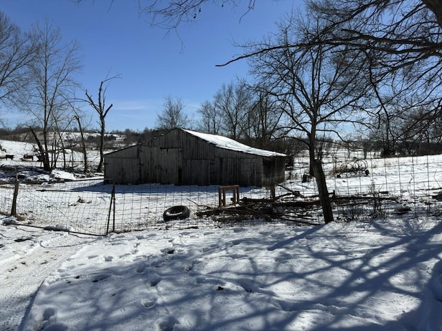 snowy yard featuring an outdoor structure and fence