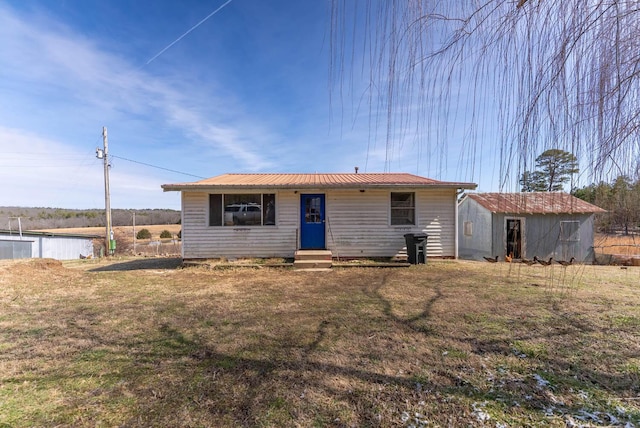 single story home with an outbuilding, a storage unit, entry steps, a front yard, and metal roof