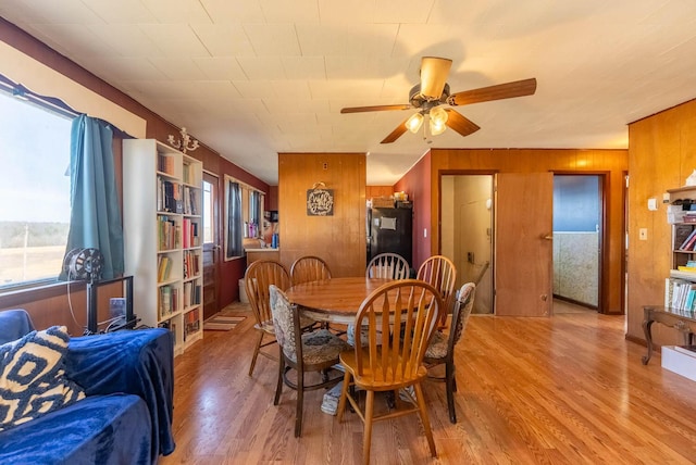 dining space featuring ceiling fan, wood walls, and wood finished floors