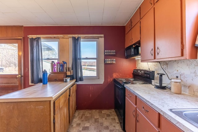 kitchen featuring black appliances, brown cabinetry, light countertops, and a healthy amount of sunlight