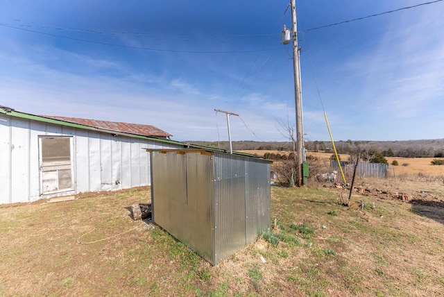 view of yard featuring an outbuilding, a rural view, and a storage unit