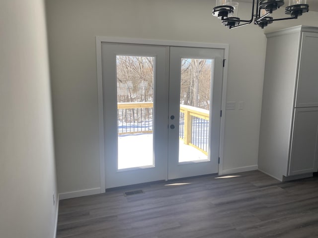 doorway to outside with french doors, dark wood-style flooring, visible vents, an inviting chandelier, and baseboards