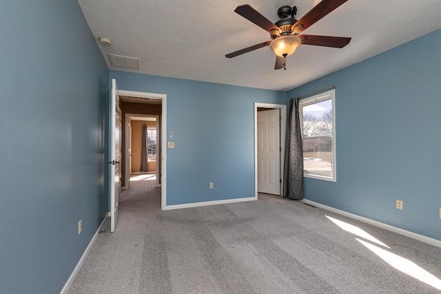 unfurnished bedroom with carpet, a textured ceiling, and baseboards