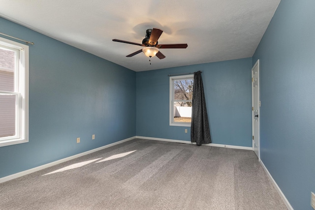 spare room with a textured ceiling, carpet flooring, a ceiling fan, and baseboards