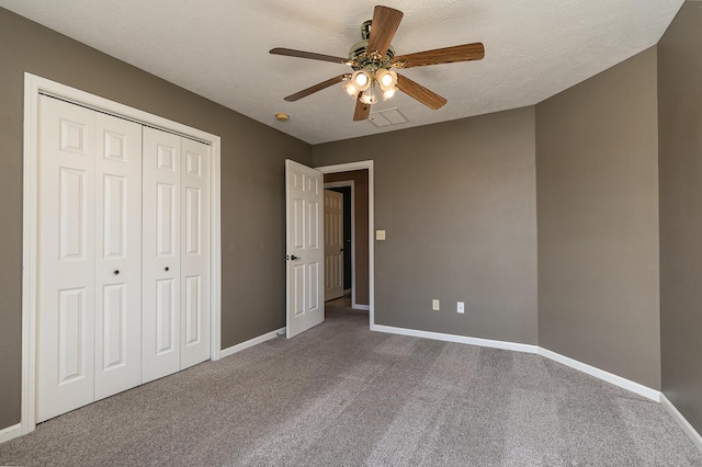 unfurnished bedroom with baseboards, ceiling fan, a textured ceiling, carpet flooring, and a closet