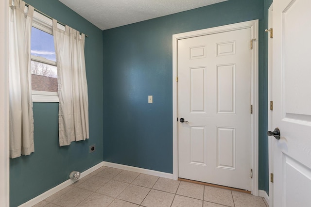 spare room with a textured ceiling, baseboards, and light tile patterned floors