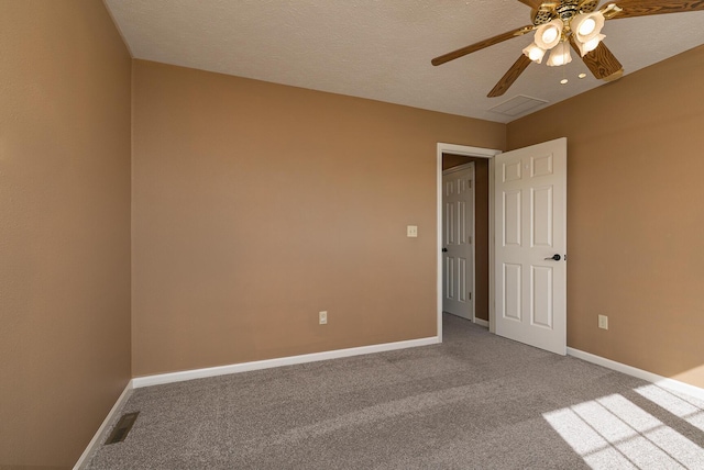 carpeted spare room featuring a ceiling fan, visible vents, and baseboards