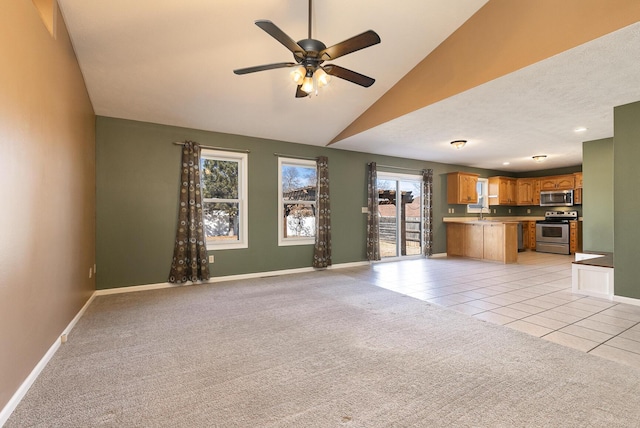 unfurnished living room featuring light tile patterned floors, ceiling fan, light colored carpet, baseboards, and vaulted ceiling