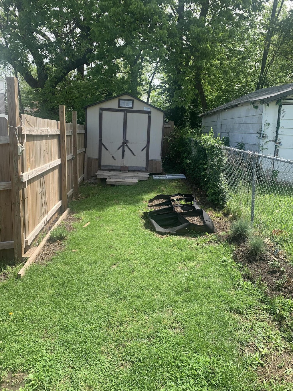 view of yard featuring an outbuilding, a fenced backyard, and a storage shed