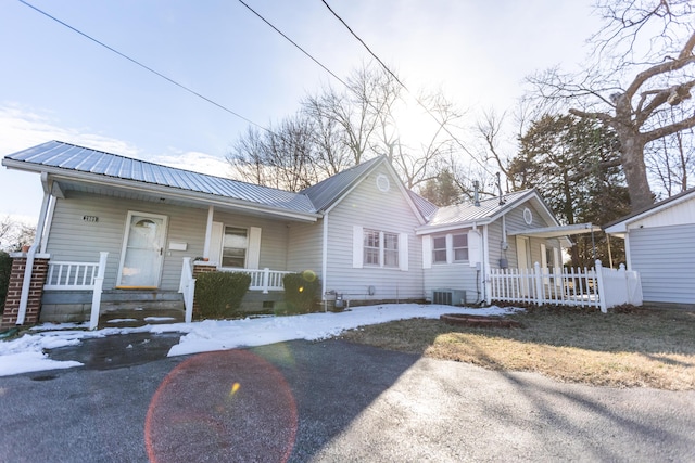 view of front of house with metal roof, covered porch, central AC, fence, and crawl space