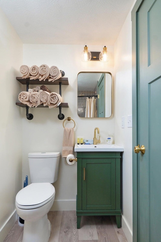 bathroom with vanity, wood finished floors, toilet, and baseboards