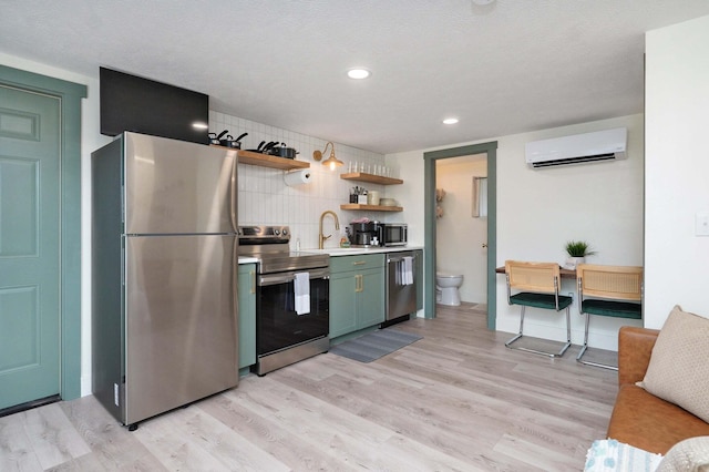 kitchen with light wood finished floors, open shelves, light countertops, a wall mounted AC, and appliances with stainless steel finishes