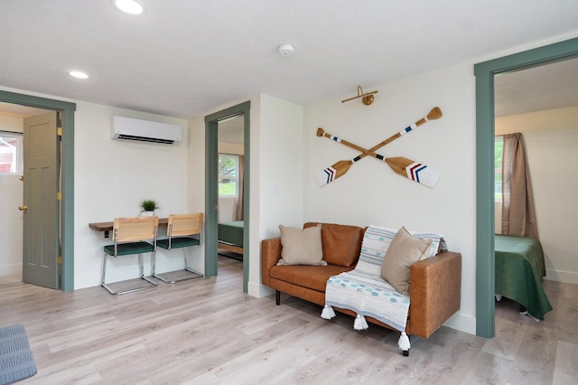 living area featuring a healthy amount of sunlight, baseboards, an AC wall unit, and wood finished floors