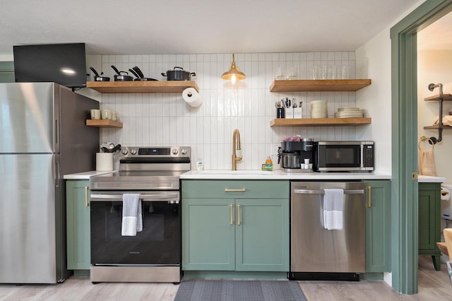 kitchen featuring green cabinets, open shelves, appliances with stainless steel finishes, and decorative backsplash