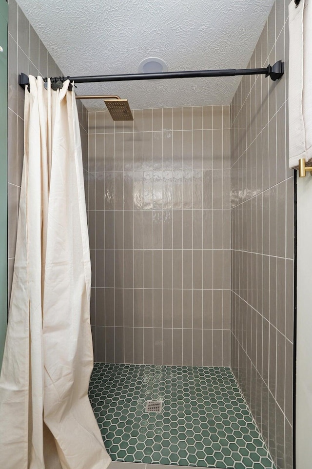 full bath featuring a textured ceiling and tiled shower