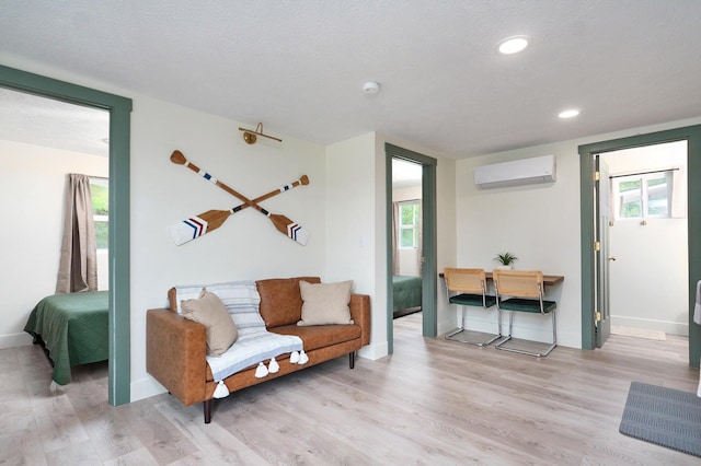 living area with baseboards, wood finished floors, a wall mounted air conditioner, a textured ceiling, and recessed lighting