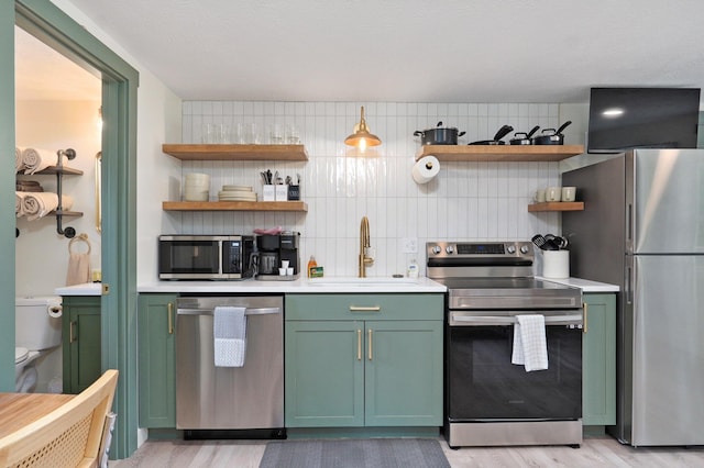 kitchen featuring open shelves, light countertops, green cabinets, appliances with stainless steel finishes, and a sink