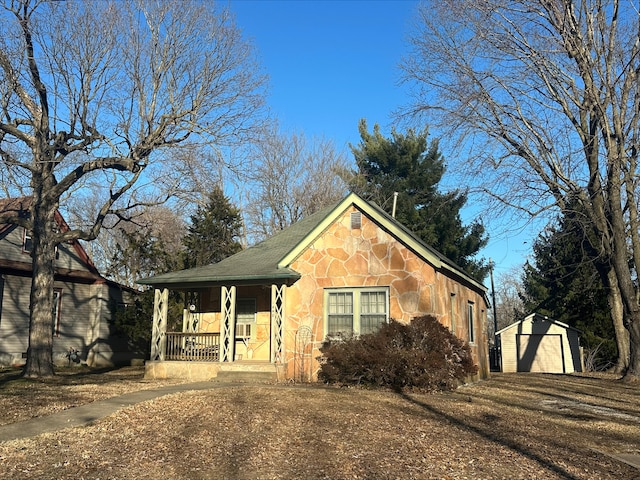 view of front of home featuring stone siding, a detached garage, an outbuilding, covered porch, and a storage unit