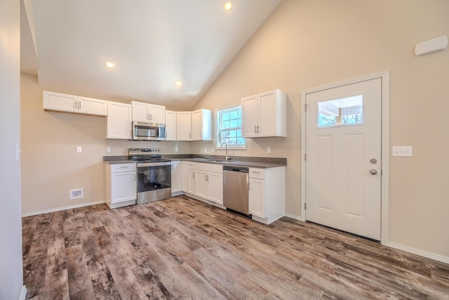 kitchen with stainless steel appliances, dark countertops, and white cabinetry