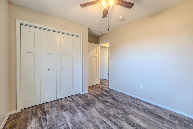 unfurnished bedroom with dark wood-type flooring, a closet, baseboards, and a ceiling fan