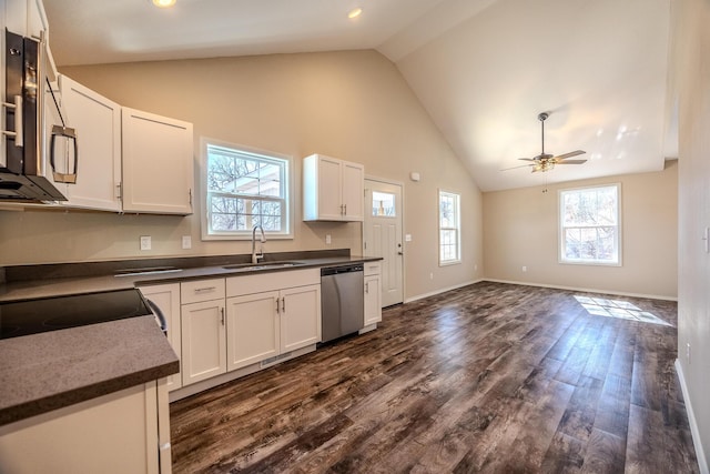 kitchen featuring dark countertops, appliances with stainless steel finishes, open floor plan, white cabinets, and a sink