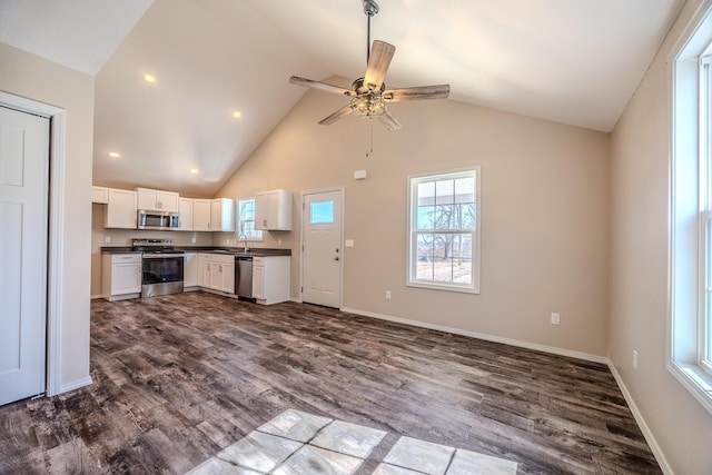 kitchen with white cabinets, dark wood finished floors, dark countertops, open floor plan, and stainless steel appliances