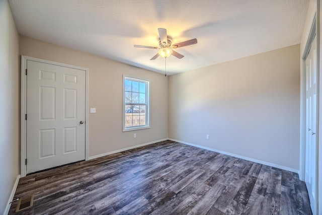 unfurnished room featuring ceiling fan, dark wood-type flooring, visible vents, and baseboards