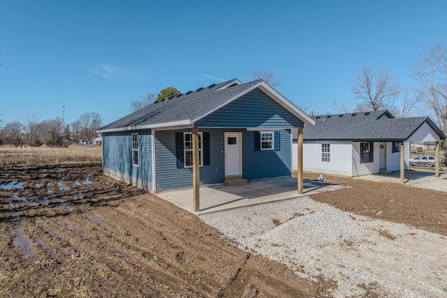 view of front of home with a shingled roof and a patio area