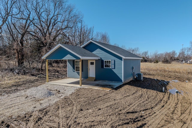 view of front of house featuring a patio, a shingled roof, and central AC unit