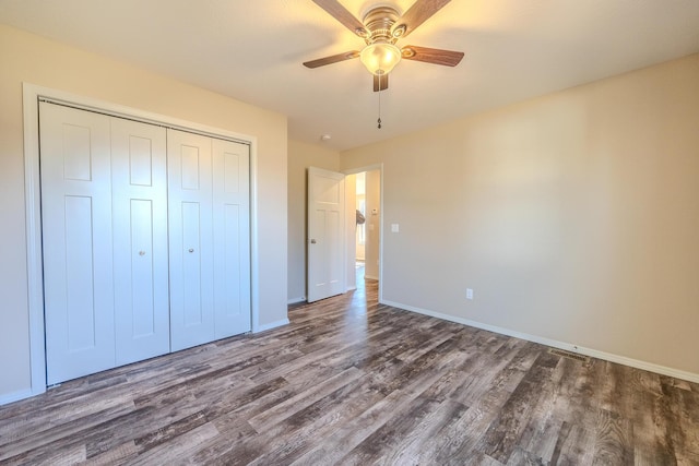 unfurnished bedroom with a closet, dark wood-style flooring, baseboards, and a ceiling fan