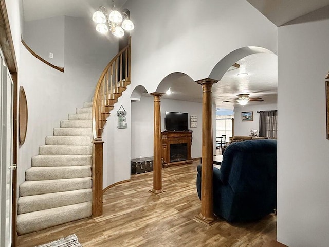 living room featuring arched walkways, a fireplace, decorative columns, and wood finished floors