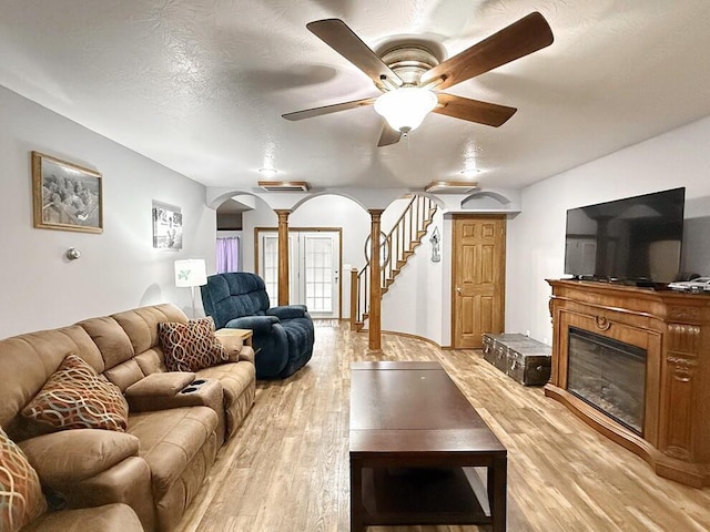 living area with light wood-style floors, stairway, arched walkways, and ornate columns