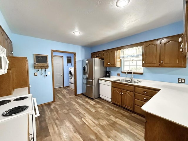 kitchen featuring white appliances, dark wood-type flooring, a sink, light countertops, and washer / clothes dryer