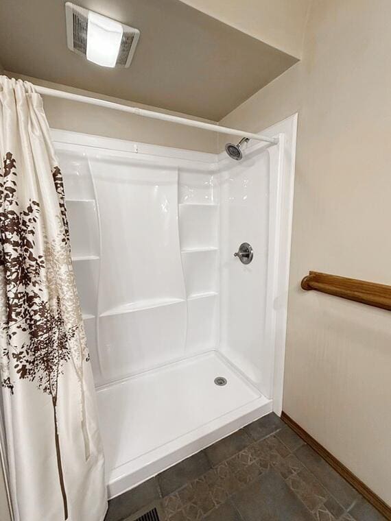 full bath with a stall shower, visible vents, and baseboards