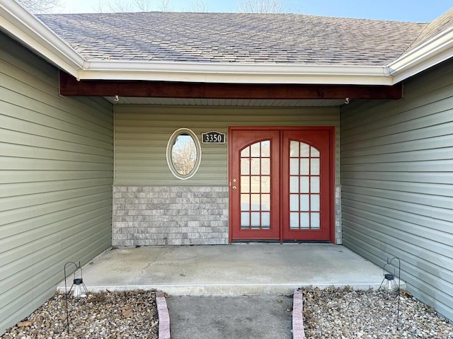 doorway to property with french doors and roof with shingles