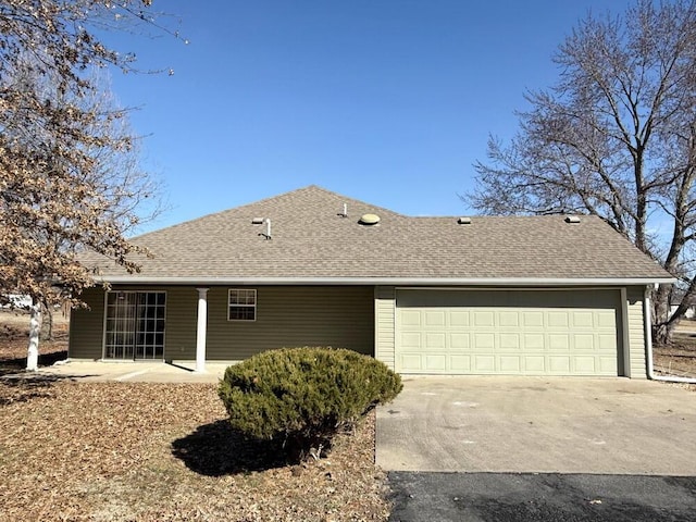 back of property featuring driveway, an attached garage, and roof with shingles