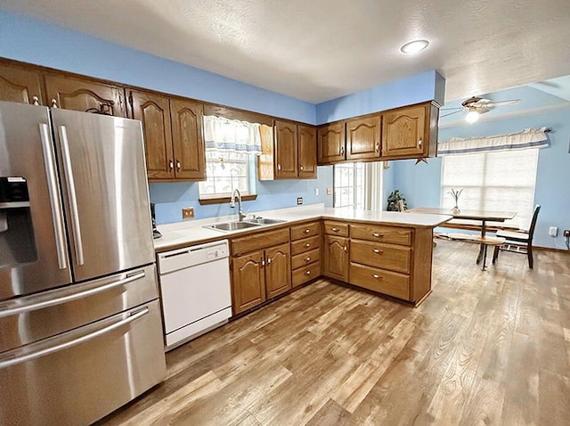 kitchen with brown cabinets, light countertops, white dishwasher, a sink, and stainless steel fridge with ice dispenser