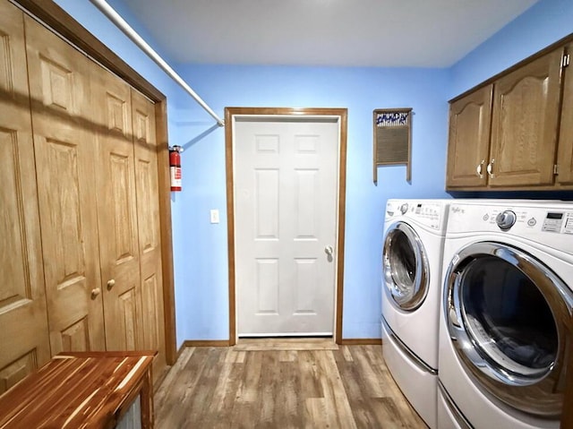 washroom featuring washer and clothes dryer, wood finished floors, cabinet space, and baseboards