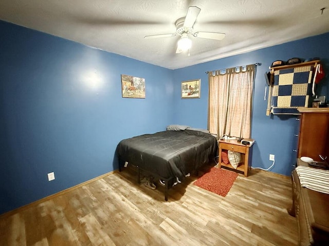 bedroom with a textured ceiling, wood finished floors, and a ceiling fan