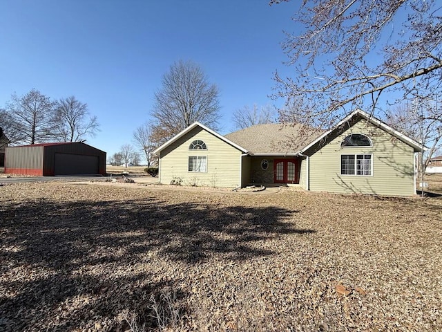 back of property with a detached garage and an outbuilding