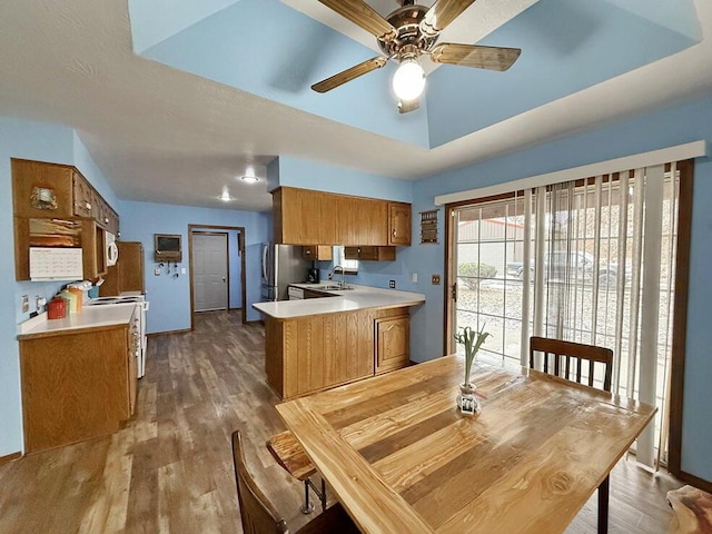 kitchen featuring light countertops, brown cabinetry, a peninsula, and a raised ceiling