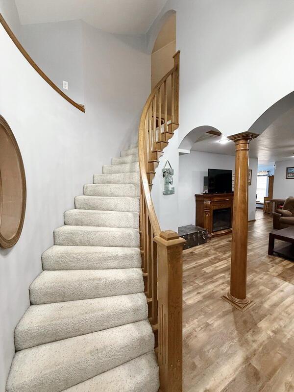 stairway with arched walkways, decorative columns, and wood finished floors