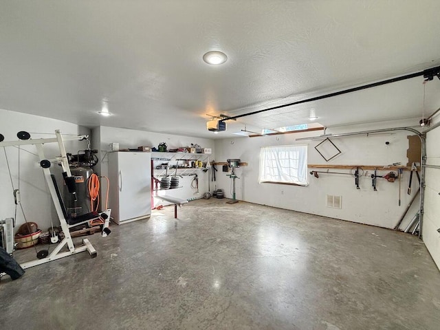 garage featuring a garage door opener and freestanding refrigerator