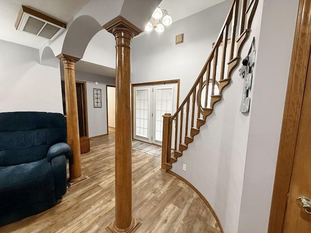 entrance foyer with light wood-style flooring, stairway, and decorative columns