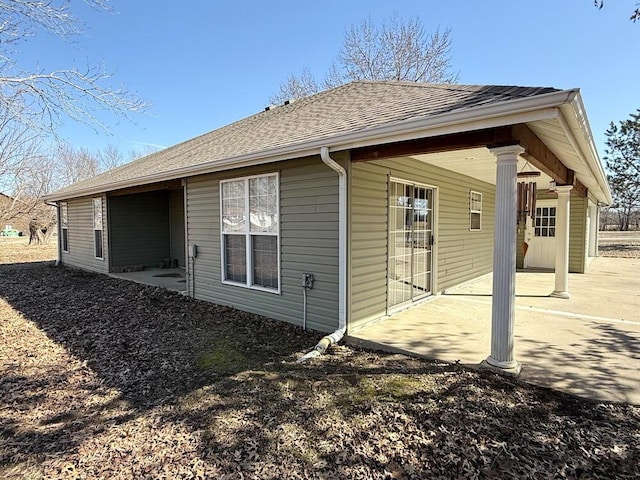 back of house featuring a patio area and roof with shingles